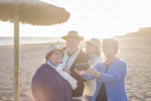 mixed ages caucasian group of four people three women and one man stay together with joy and happiness like a family with mothers father and daughter. summer leisure at the beach during a bright sunset sunlight
