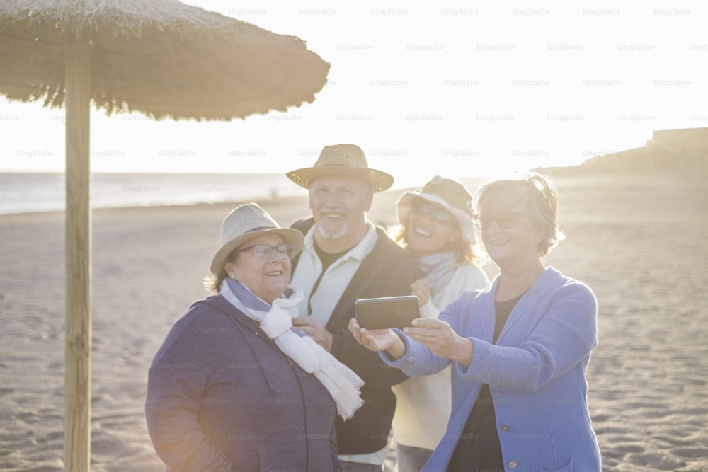 혼합 연령 백인 그룹 4 명 3 명의 여성과 1 명의 남성은 어머니 아버지와 딸이있는 가족처럼 기쁨과 행복으로 함께 지냅니다. 밝은 일몰 햇살을 받으며 해변에서의 여름 레저