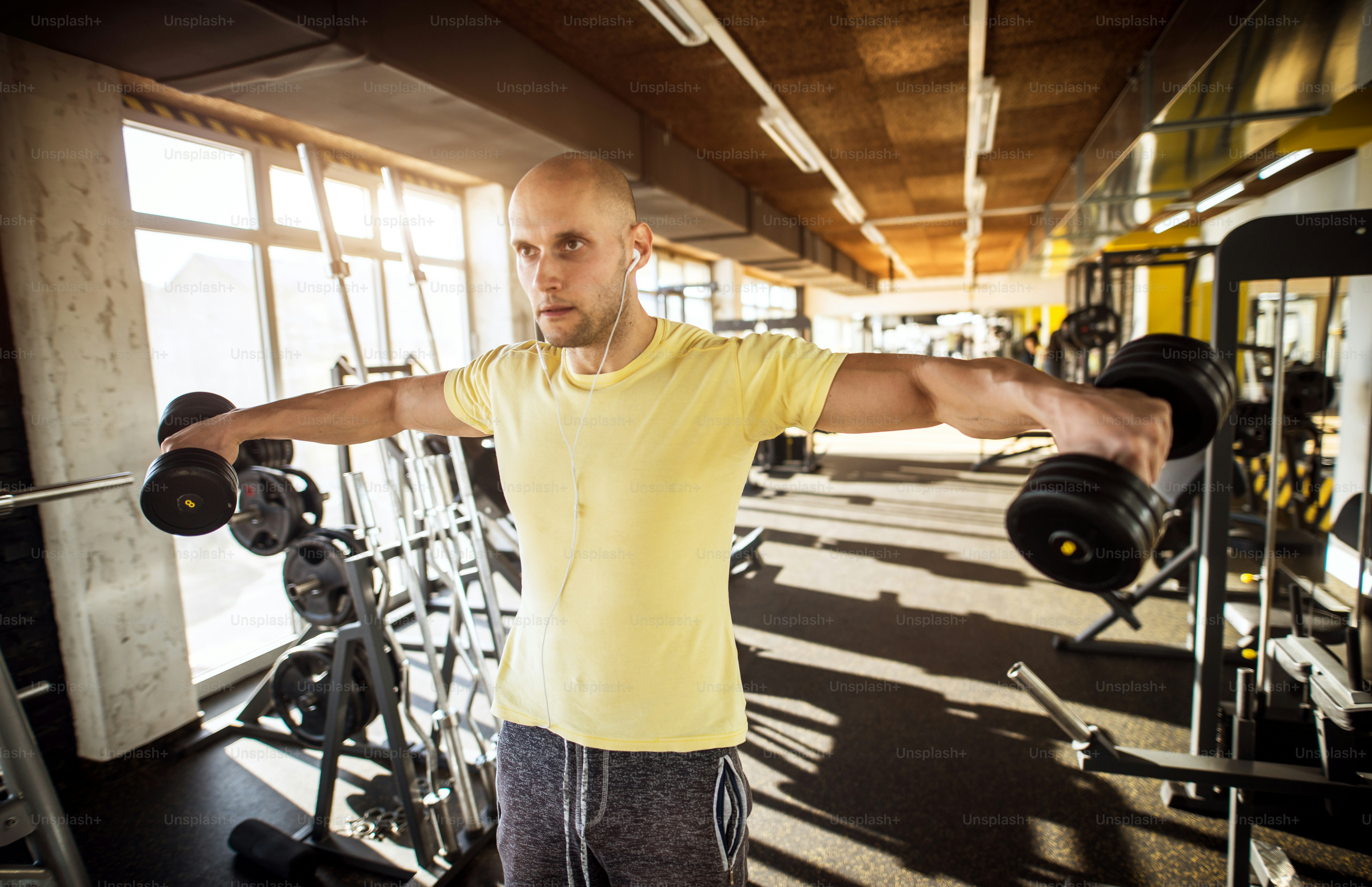 両手を広げてダンベルを上げ ジムで音楽を聴く 強い筋肉質のアクティブな健康な若い男性のポートレート の写真 Unsplashで見つけるスポーツの無料写真