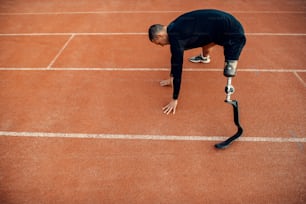 A fit sportsman with artificial leg working out at stadium on running track.