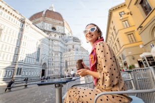 Jovem mulher elegante gosta de café e bela vista sobre a famosa catedral Duomo em Florença. Conceito de visitar marcos italianos e passar o tempo durante a viagem. Ideia de estilo de vida italiano