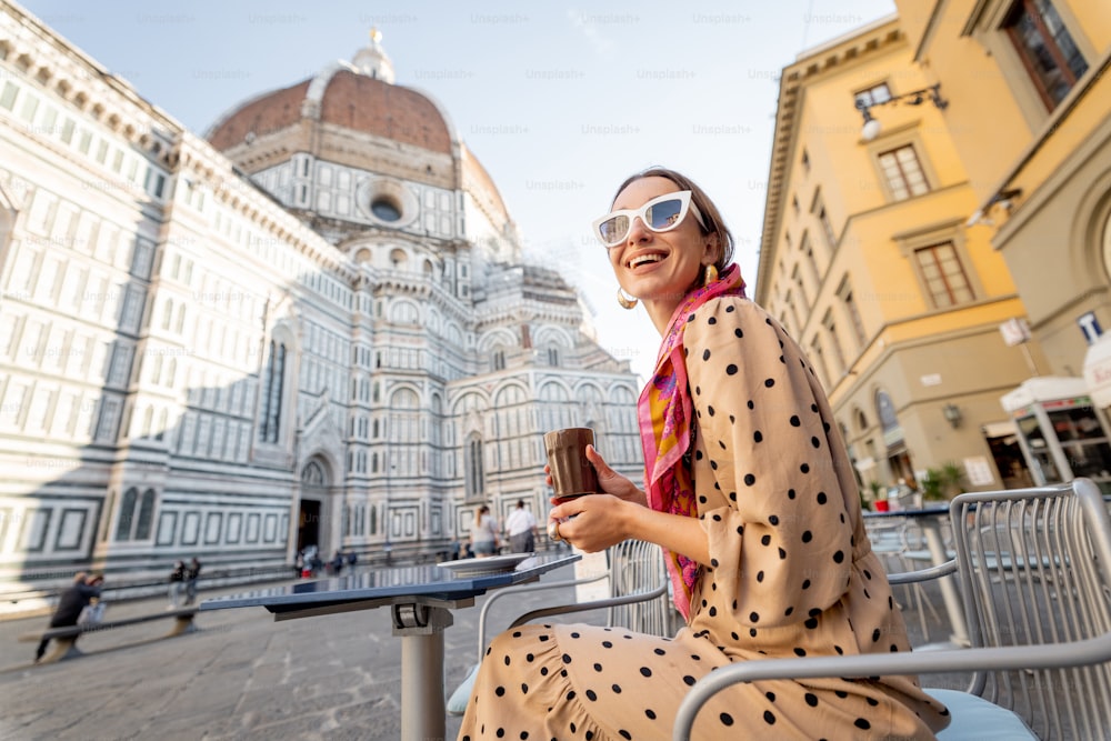 Una mujer joven y elegante disfruta del café y de una hermosa vista de la famosa catedral del Duomo en Florencia. Concepto de visitar lugares emblemáticos italianos y pasar tiempo mientras viaja. Idea del estilo de vida italiano