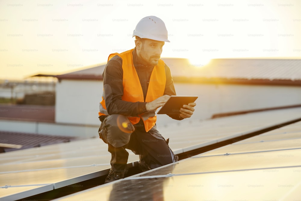 Hoher Solarenergieverbrauch. Ein Handwerker, der ein Tablet zum Testen von Sonnenkollektoren verwendet.