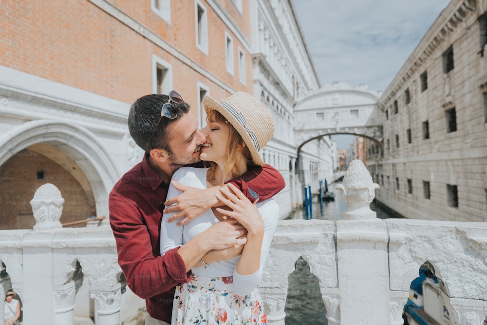 ヴェネツィアの街で楽しんでいる美しいロマンチックなカップル - 有名な観光で一緒にイタリアを旅行する観光客 - 休日と幸せなライフスタイルのコンセプト