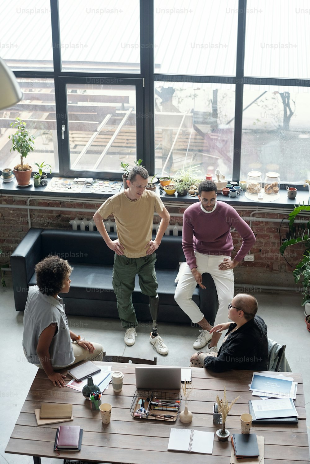 Un grupo de jóvenes compañeros de trabajo en ropa casual discuten ideas para un nuevo proyecto empresarial en una reunión en una gran oficina