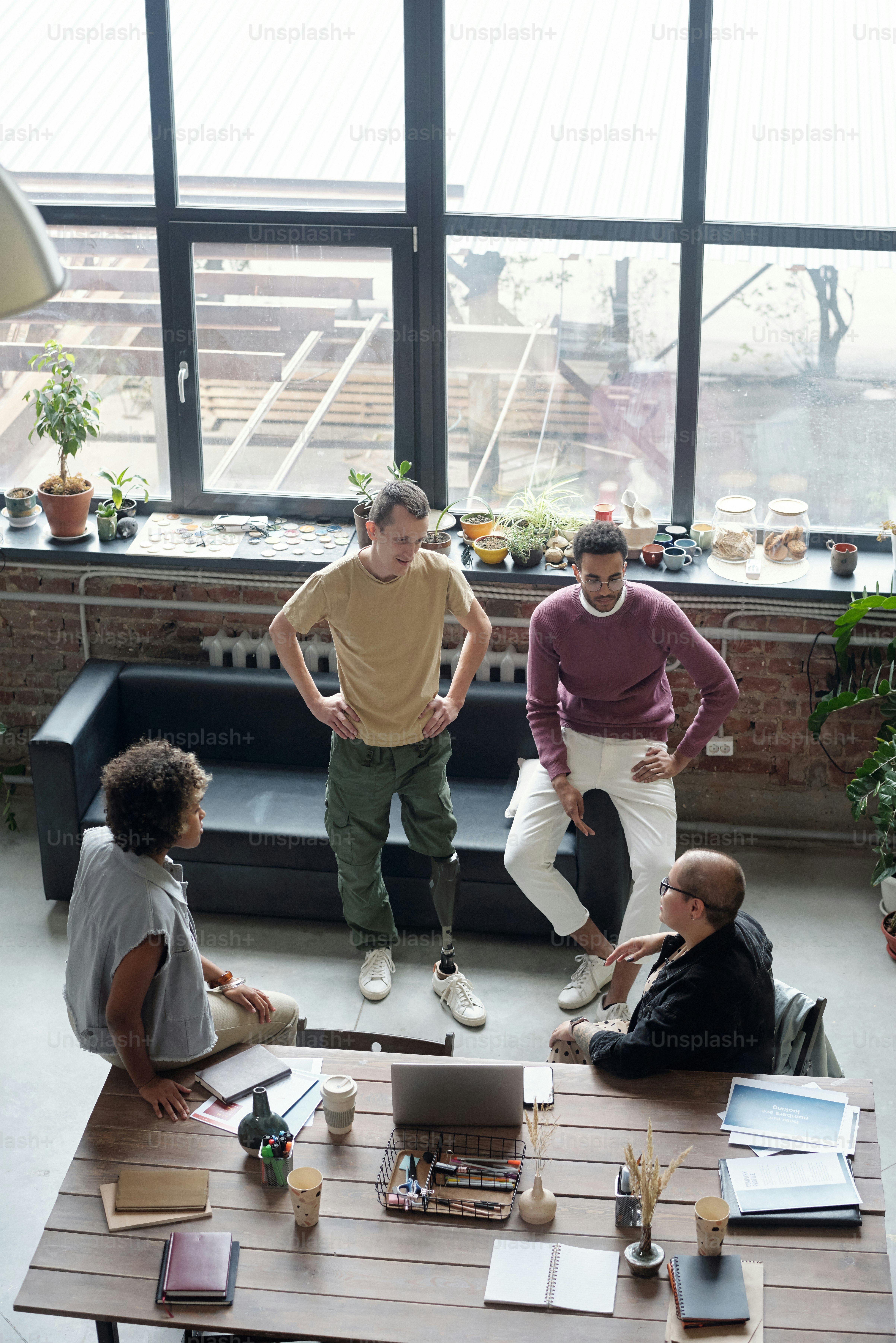 Group of young co-workers in casualwear discussing ideas for new business project at meeting in large office