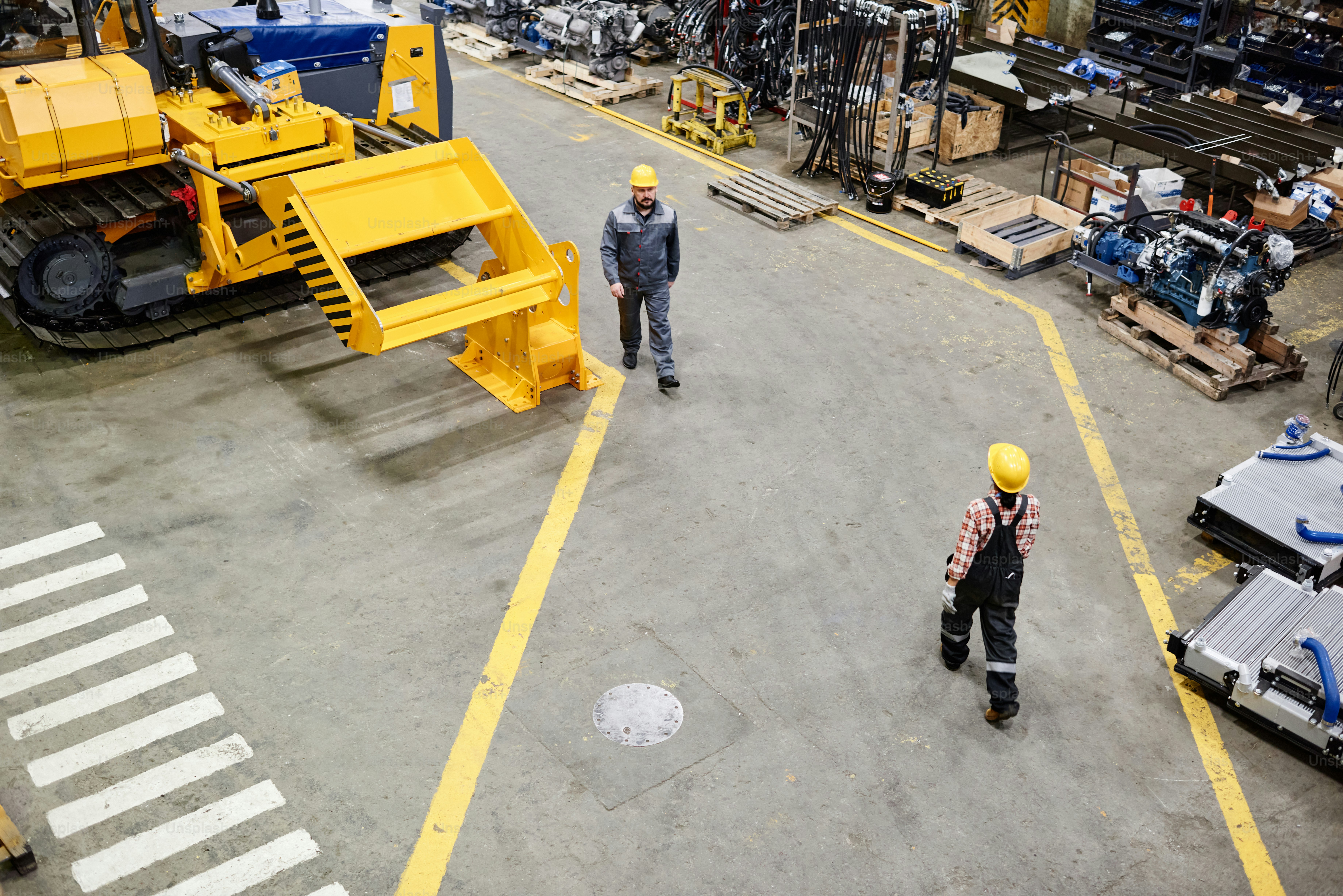 Dois trabalhadores da planta industrial movendo-se um em direção ao outro enquanto caminham ao longo do armazém de distribuição ou oficina