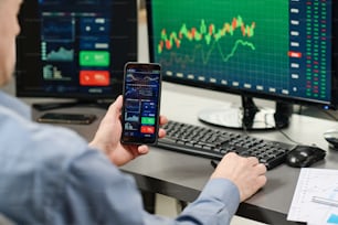 Investment specialist working in stock trading industry watching charts and graphs of currency on smartphone