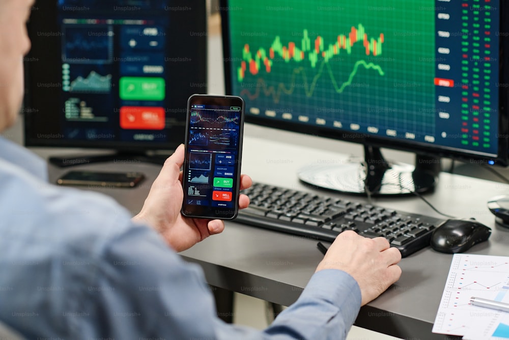 Anlagespezialist, der in der Aktienhandelsbranche arbeitet und Charts und Grafiken der Währung auf dem Smartphone beobachtet
