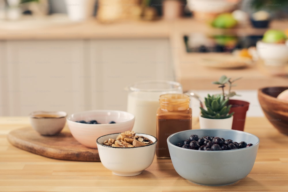 Group of bowls and jars with ingredients for smoothie on kitchen table