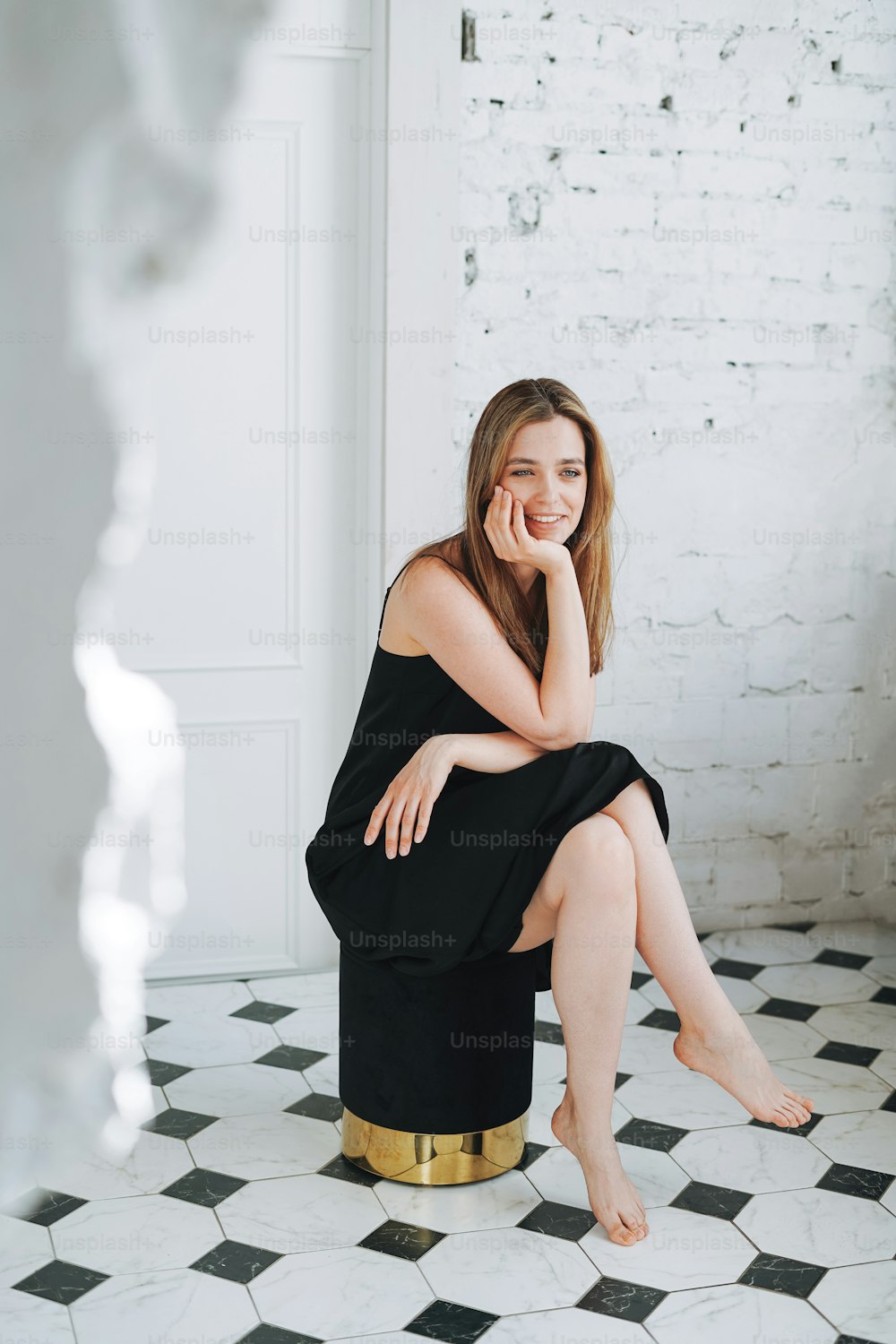 Fashion beauty portrait of happy young woman with long hair on evening elegant black dress in white interior