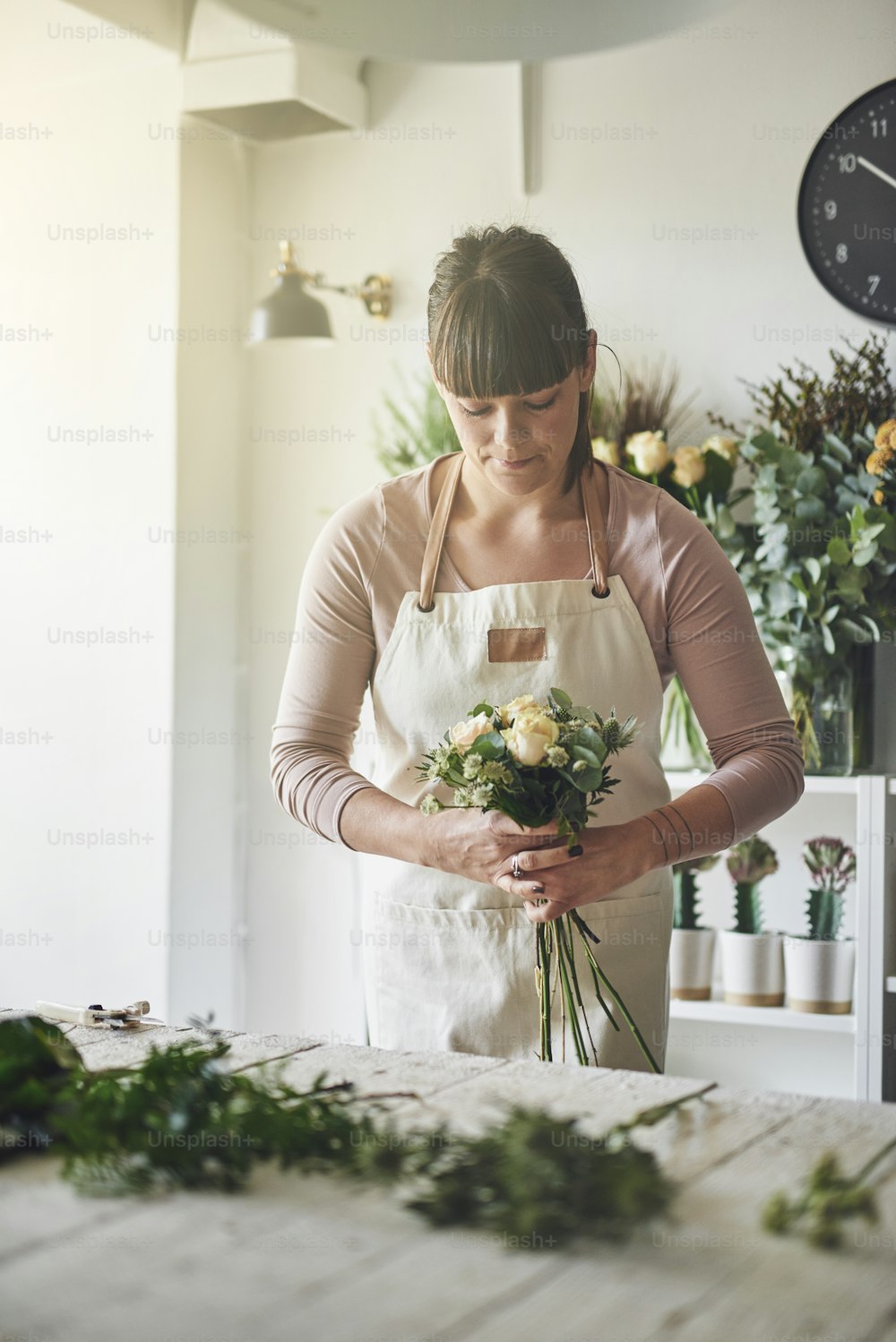 Young female florist working alone at a table in her flower shop making a bouquet of mixed flowers