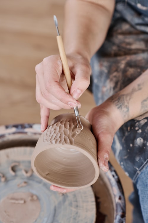 Hands carving detailed patterns into clay