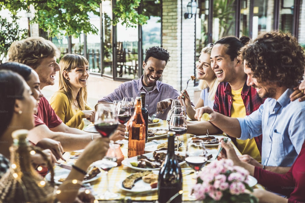 Happy multiracial family having bbq dinner party outside - Group of friends dining at garden restaurant - Young people enjoying lunch break together - Food and beverage lifestyle concept