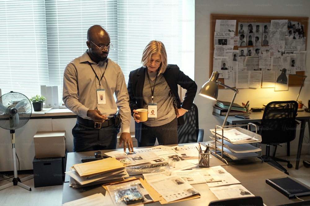 Two interracial FBI agents making suggestions about finding out gang leader while looking through personal data of criminals