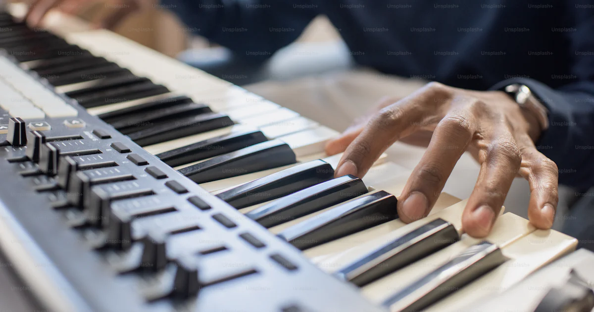 Fingers of young African man pressing keys of piano keyboard while ...