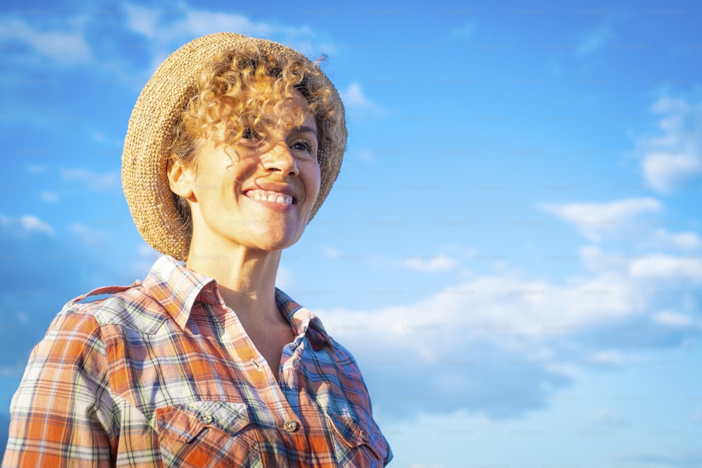 Retrato alegre de uma mulher adulta bonita sorrindo e desfrutando de atividade de lazer ao ar livre contra um céu azul ao fundo. Feliz senhora admirando na frente dela. Pessoas serenas e confiantes e alegres