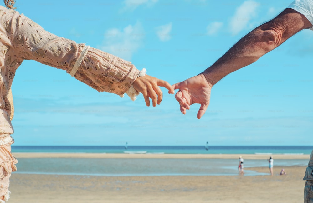 Back view of man and woman hand to hand together in front of a tropical beach. Love and relationship couple people holding hands and enjoying leisure in summer holiday vacation. Blue Ocean and sky