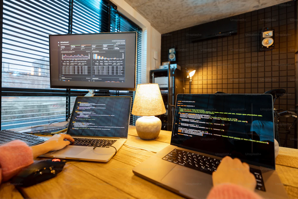 Developer typing at a home desk with multiple screens