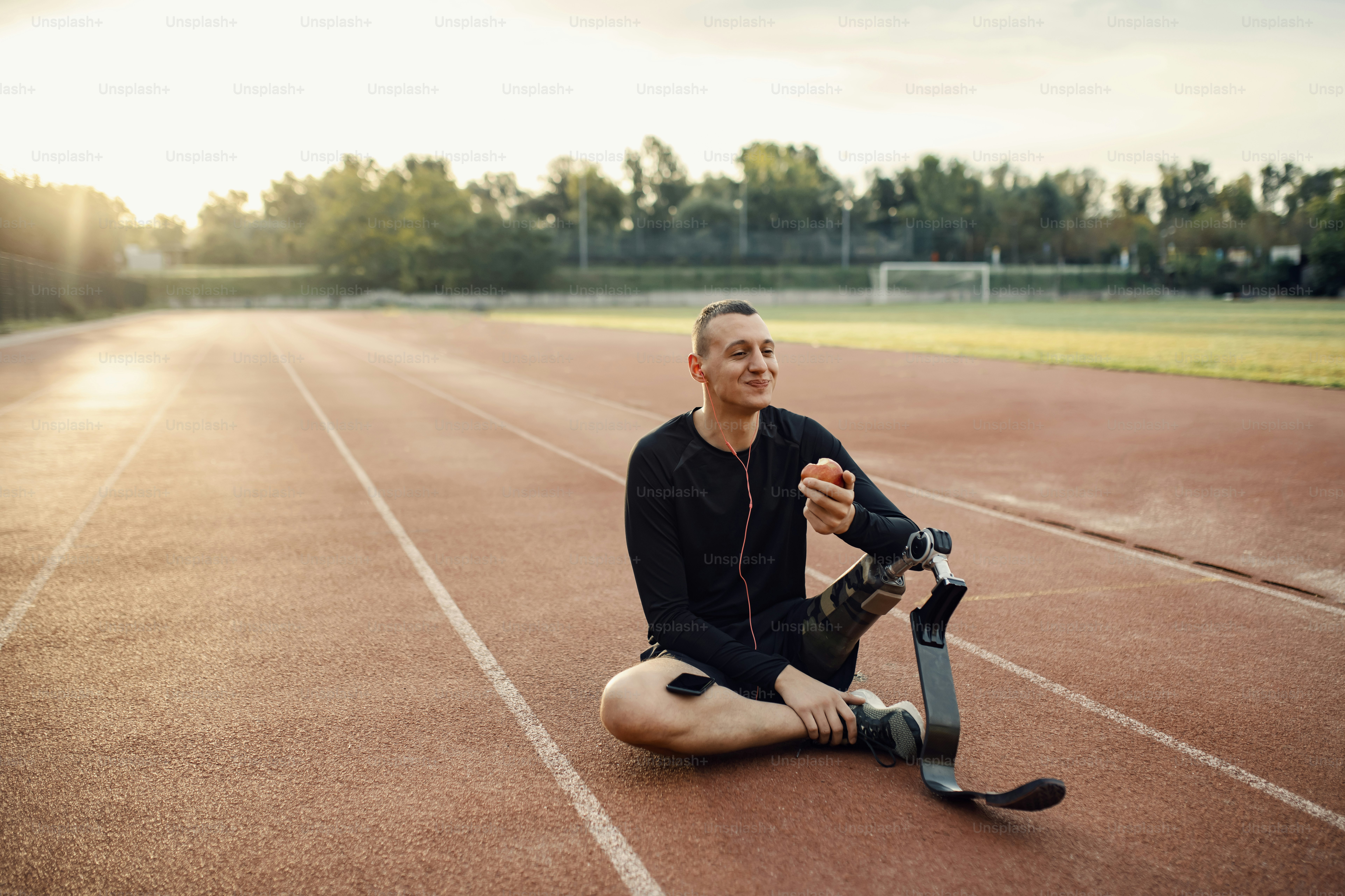スポーツを休んでリンゴを食べ、音楽を聴きながらくつろぐ障害者スポーツマン。