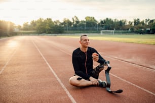 Ein behinderter Sportler, der eine Pause vom Sport macht, Apfel isst und bei Musik entspannt.