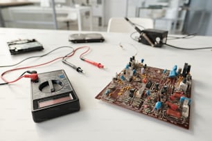 Scheda madre del computer e del dispositivo di trasmissione con pinzette elettriche sul posto di lavoro del riparatore in laboratorio