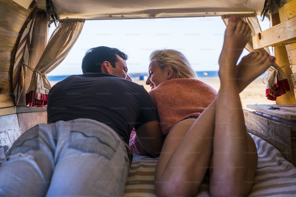 nice beautiful young caucasian couple lay down in a van with ocean view. together friendly and relationship concept for alternative traveler near the beach