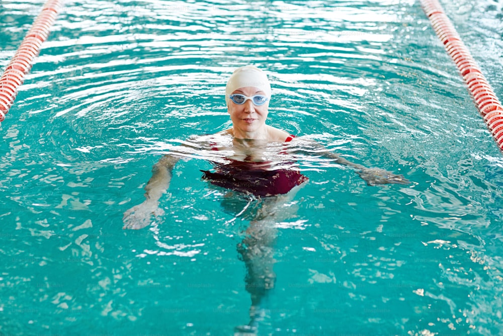 Nageuse active en maillot de bain s’entraînant dans l’eau à loisir dans un centre sportif
