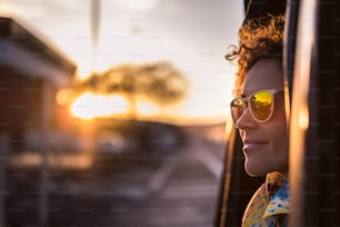 mulher bonita viajar em um carro olhando para fora e apreciar a luz do pôr do sol dourado em seu rosto. estilo de vida agradável e emoções pacíficas viajando ao redor do mundo