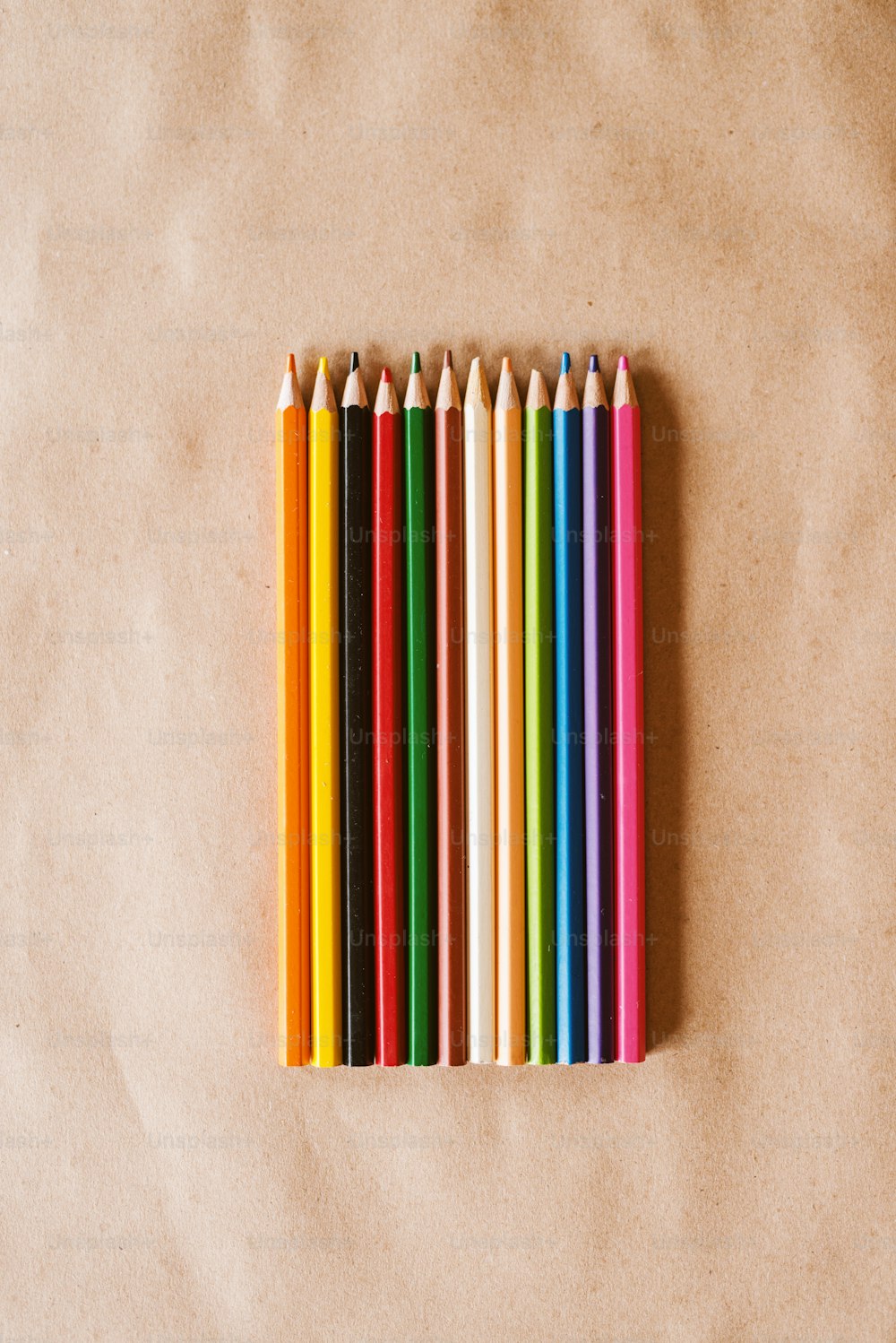 Row of colourful wooden crayons on the desk.