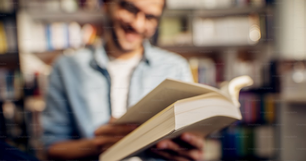 Close up book view while smiling young man reading in the high school ...