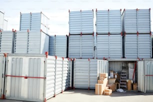 Vários grandes recipientes de armazenamento com amontoado de caixas por perto e suprimentos de trabalho em um deles