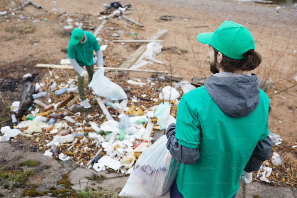 Un petit groupe de gars de Greenpeace ramasse des déchets sur le sol dans un territoire abandonné