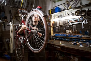 Professional young man cleaning bicycle in the workshop.