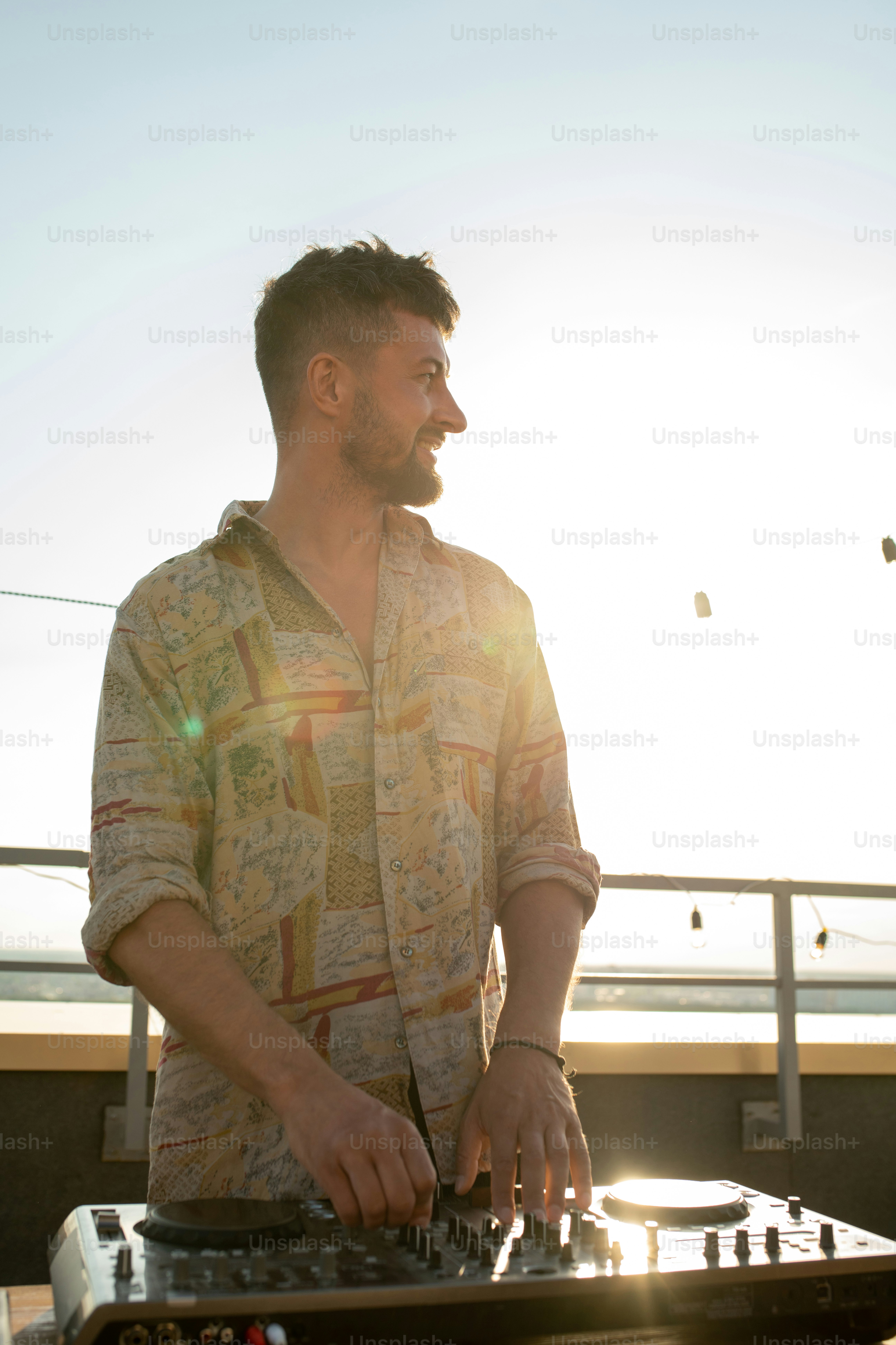 Young bearded deejay standing by soundboard in front of camera at ...
