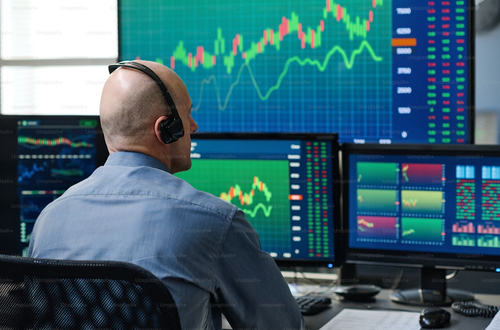 Vista posteriore di un uomo caucasico maturo irriconoscibile che indossa cuffie che monitorano le statistiche di trading azionario