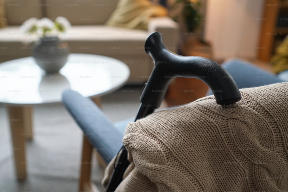 Nahaufnahme der Krücke für ältere Person, die sich auf den Stuhl im leeren Raum stützt