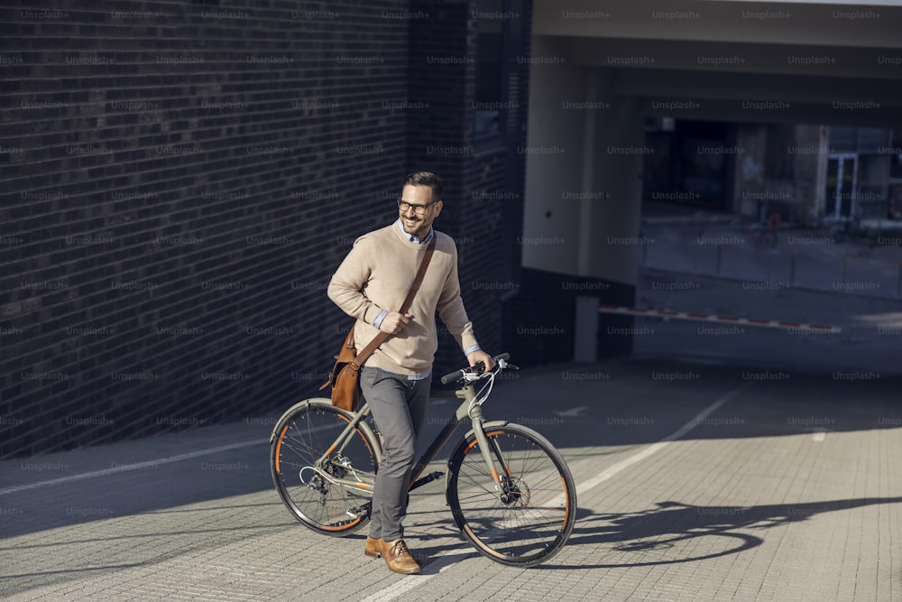Un uomo di città che spinge la sua bicicletta sulla strada.