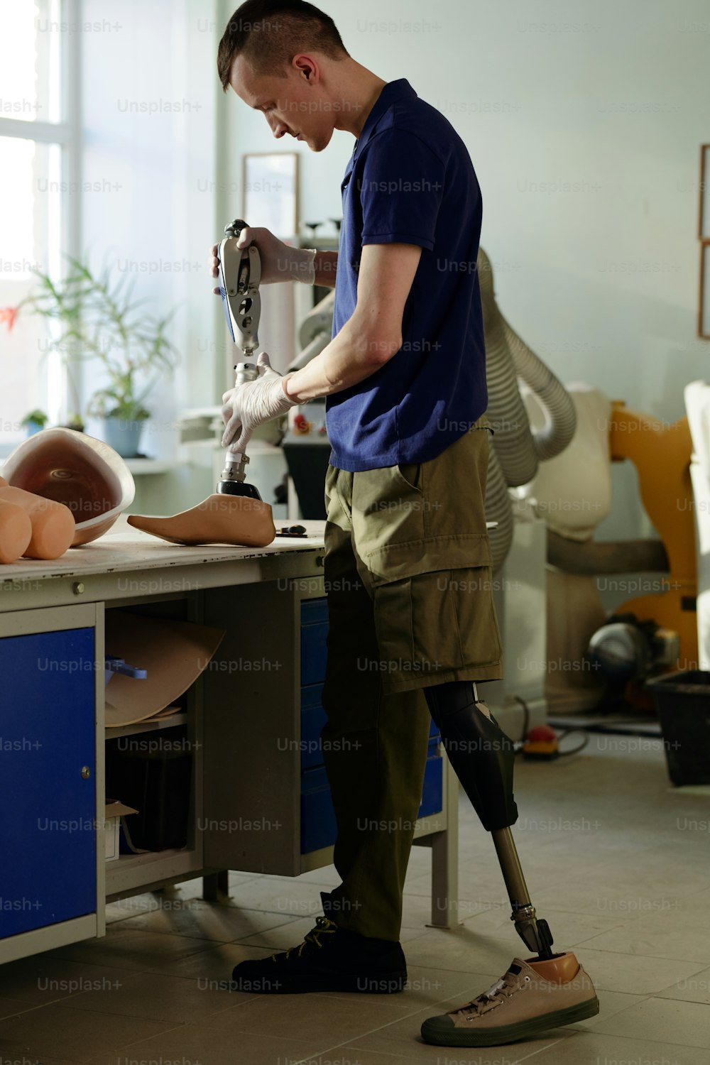 Operaio di una moderna fabbrica di produzione di protesi che assembla un nuovo arto artificiale unendo insieme due parti della sezione inferiore della gamba