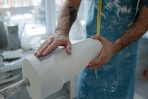 Hands of young contemporary worker of prosthetic manufactory polishing plaster cast with piece of sandpaper