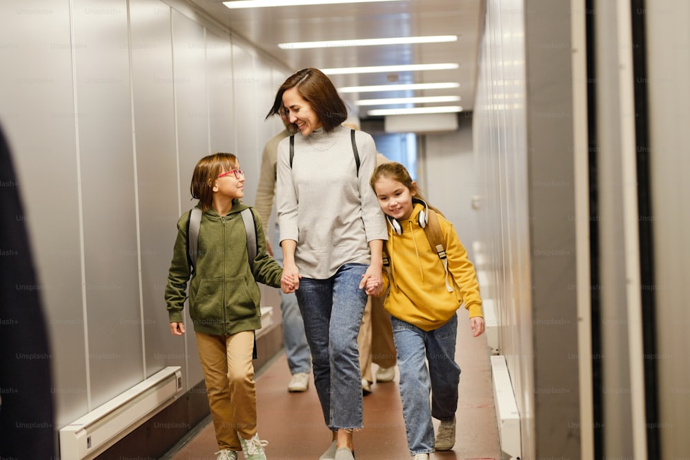 Happy mother walking along the airport terminal together with her children for boarding they going for vacation