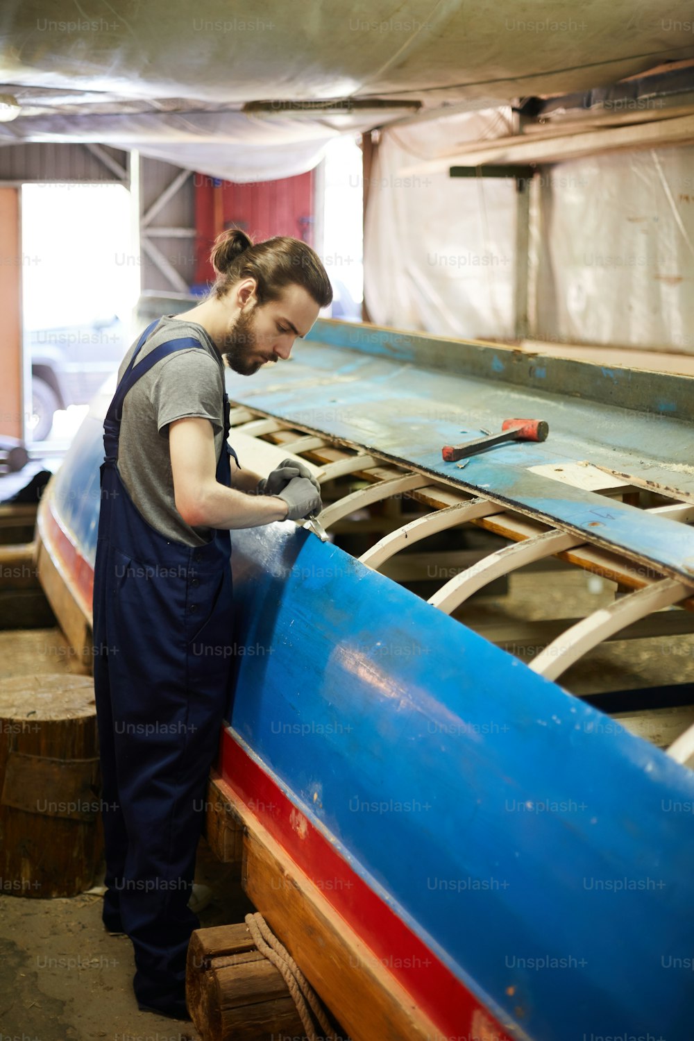 格納庫や作業場で新造船に取り組んでいるオーバーオールを着た若い造船業者
