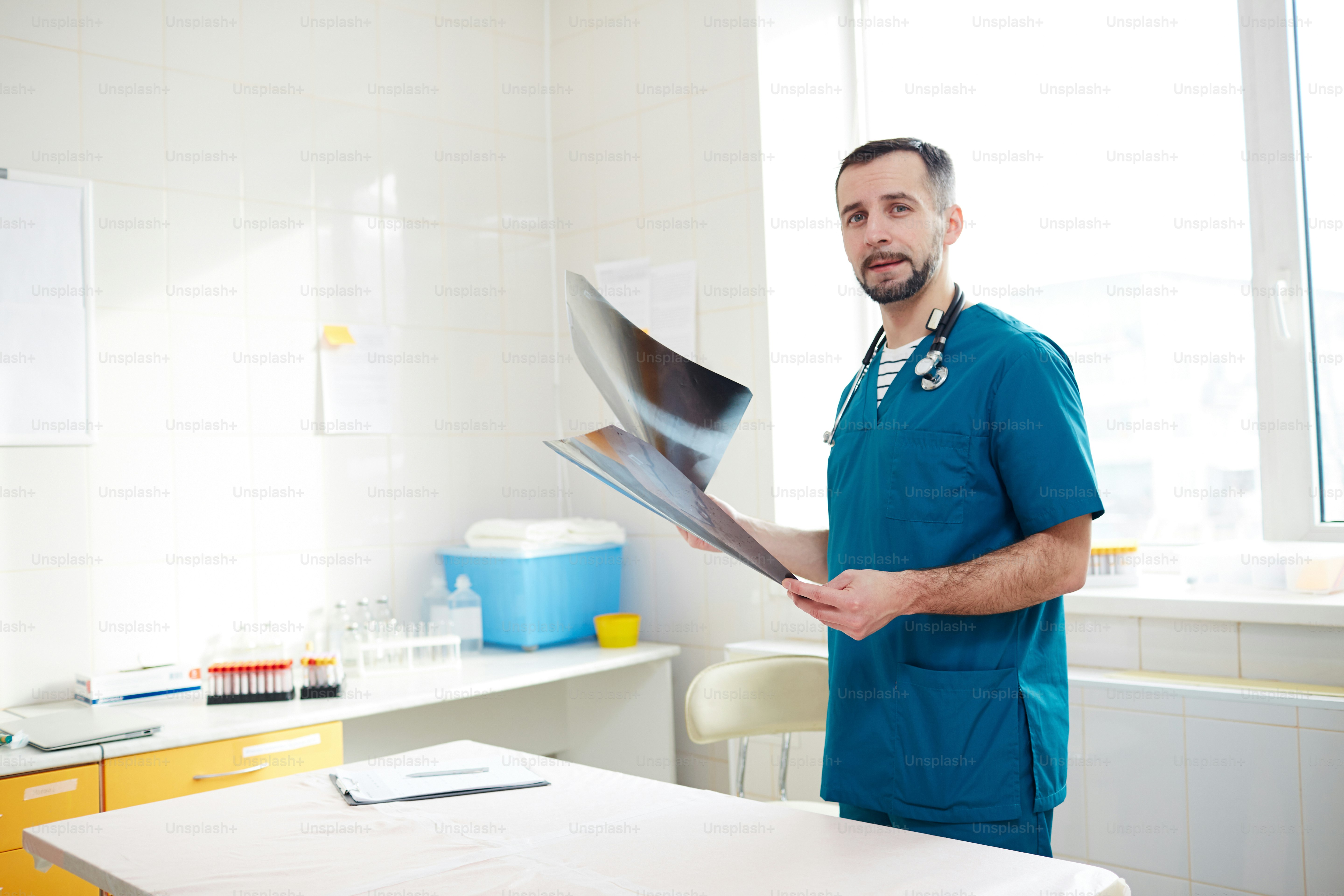 Young vet radiologist with x-ray images looking at camera by his workplace