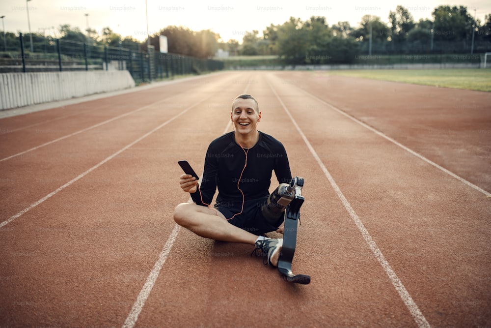 A happy sportsman with prosthetic leg relaxing at stadium with music.