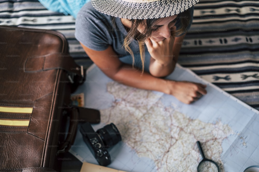 Woman at home planning travel vacation looking the guide map and smile - happy wanderlust lifestyle people - cheerful female people enjoy road trip program for next holidays destination