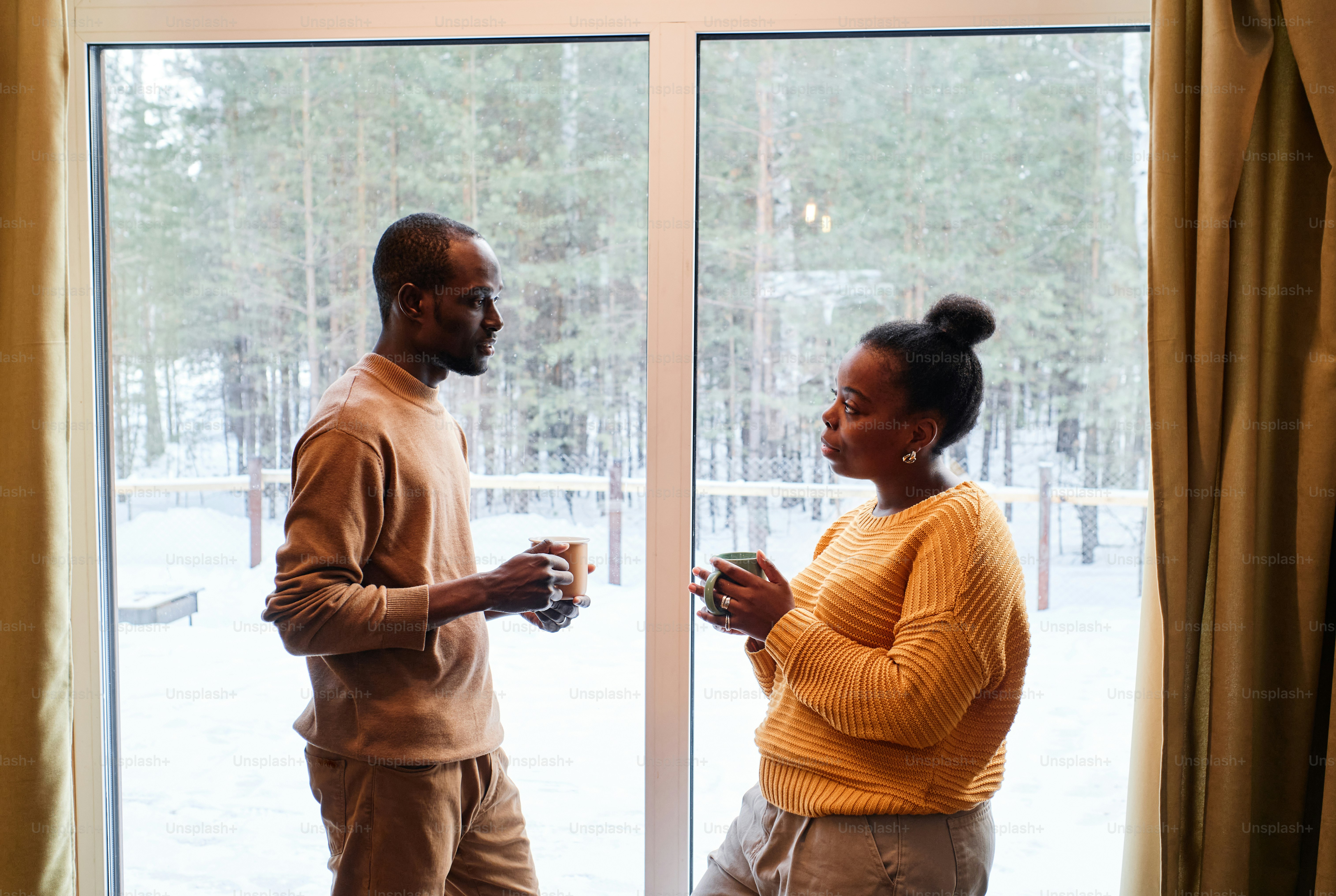 Side view of young African American couple in casualwear having tea ...