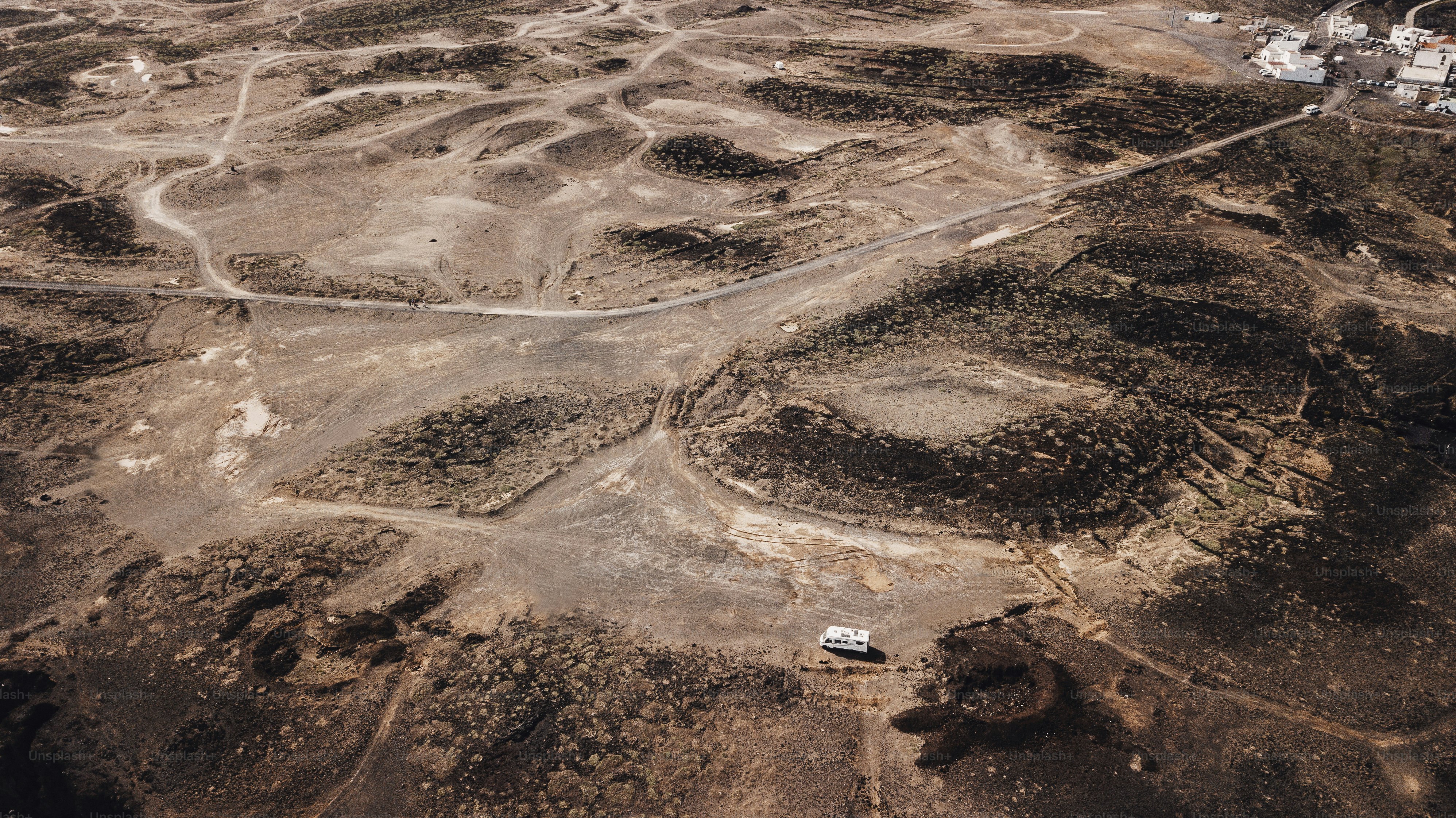 Vista aérea da van campista estacionada no deserto terrestre sozinha com estradas offroad ao redor. Conceito de liberdade e vanlife estilo de vida de viagem independente. Lugar cênico alternativo para férias de verão