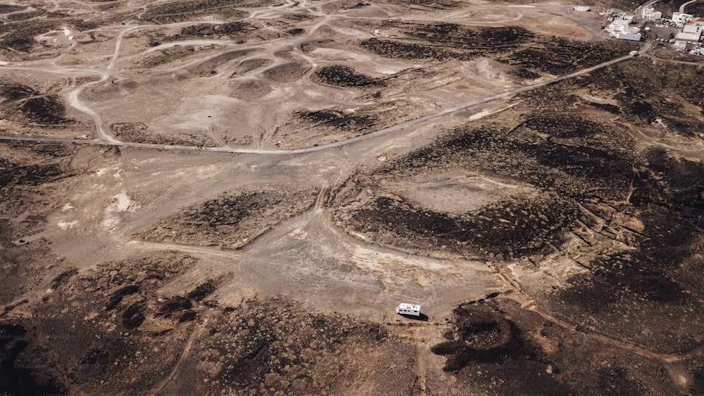 Aerial view of camper van parked in the ground desert alone with offroad roads around. Concept of freedom and vanlife independent travel lifestyle. Alternative scenic place for summer vacation