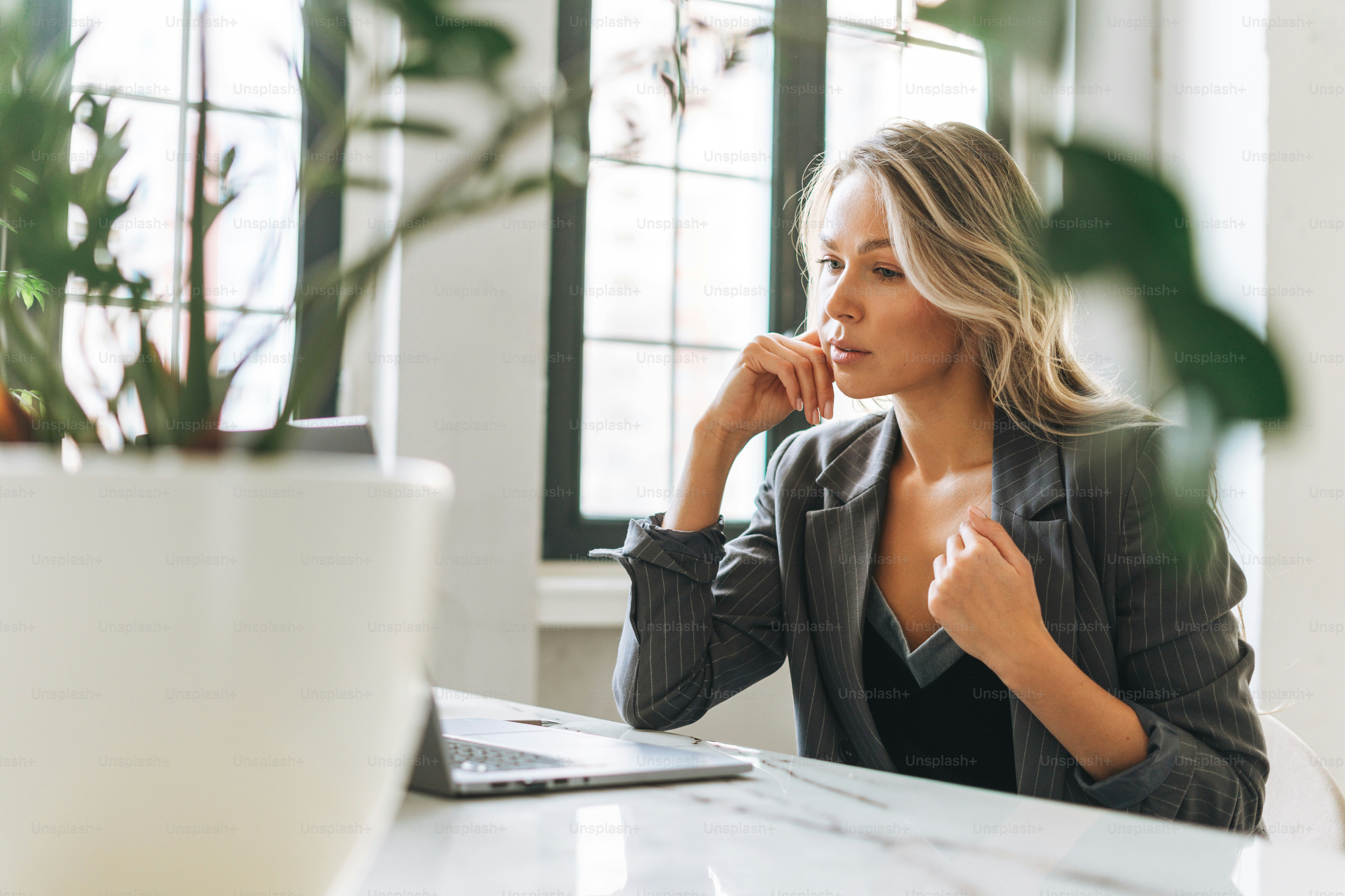Young smiling blonde woman with long hair in stylish suit working at ...