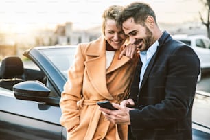 Turistas felices alquilan un coche de vacaciones - Pareja adulta que comprueba el servicio de seguro en un dispositivo de teléfono móvil inteligente - Concepto de estilo de vida y tecnología de transporte